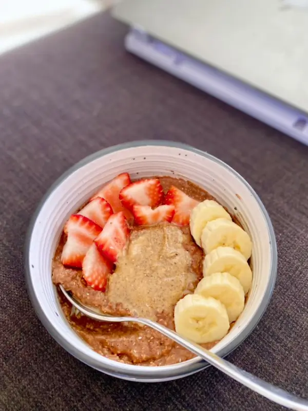 Chocolate porridge topped with peanut butter, banana and strawberries