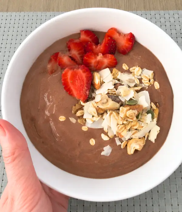 chocolate smoothie bowl topped with strawberries and shaved coconut