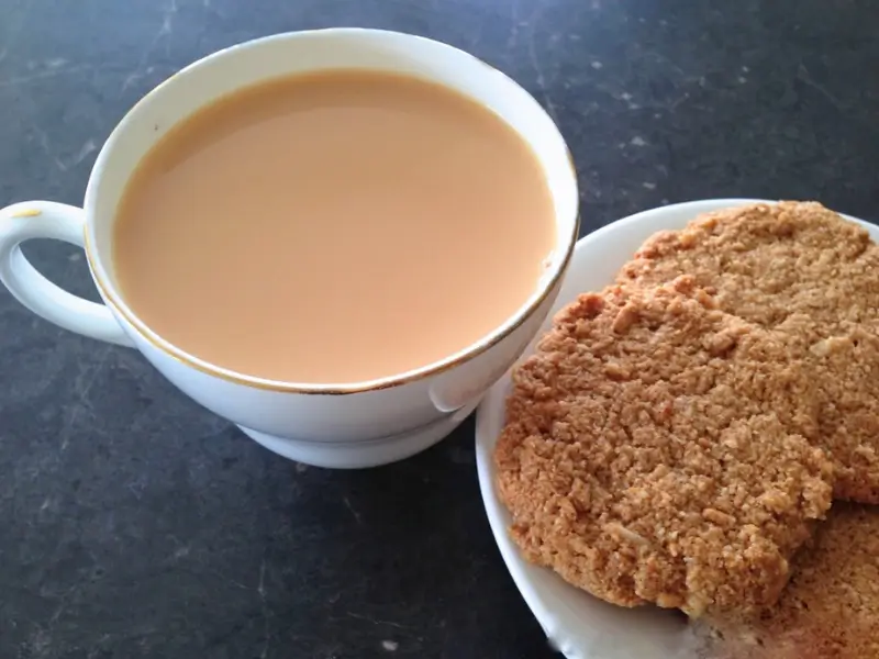 Anzac biscuits on a plate with a cup of tea