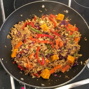 Cauliflower rice cooking on the stove top in a wok