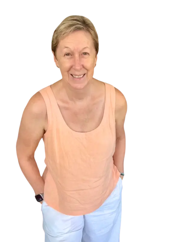 Wendy in a pale orange tank top, standing looking at the camera with hands in pockets