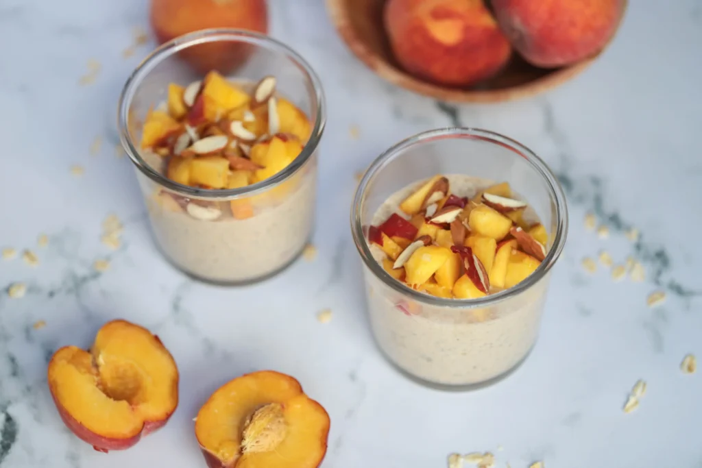Peach and honey overnight oats on a bench with sliced peaches