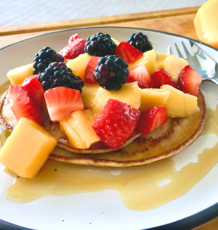 Pancakes topped with berries and maple syrup 